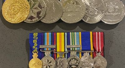The image displays several rows of medals, showcasing a variety of military and commemorative awards arranged in an orderly fashion. The medals feature intricate designs, including emblems and symbols that represent achievements and services. The top row has brighter ribbon colours, while the lower rows exhibit distinct arrangements of medals on colourful ribbons, reflecting a proud collection significant to military accolades or service recognition. This arrangement highlights the importance of medals in commemorating personal or group achievements, relevant to the business of NORTHSIDE MEDALS which focuses on trophies and recognition awards.